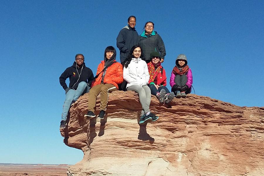 一群学生在纳瓦霍族的岩层上摆姿势拍照.